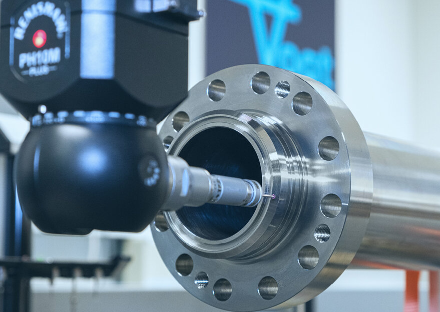 Taktile Messung im 3D-Messlabor: Eine Messmaschine mit Tastsensor tastet die Innengeometrie eines zylindrischen Metallbauteils präzise ab. Das Werkstück ist mit symmetrisch angeordneten Bohrungen versehen und wird auf Masshaltigkeit geprüft.