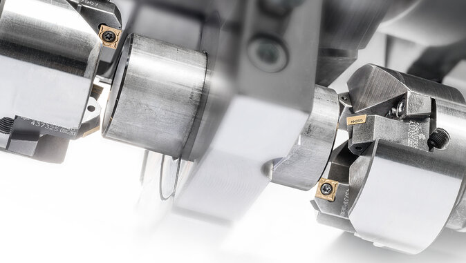 Nahaufnahme einer Rohrbearbeitungsmaschine mit eingespannten Metallrohren. Sichtbar sind präzise Spannvorrichtungen und Schneidwerkzeuge zur mechanischen Bearbeitung von Rohrabschnitten, etwa für Drehen oder Trennen.