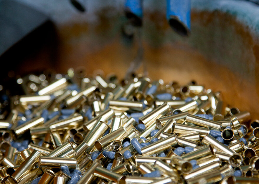 Goldfarbene Hülsen aus Metall liegen in einer Trowalisieranlage zusammen mit Schleifkörpern. Beim Trowalisieren werden die Teile entgratet und geglättet, um eine saubere Oberfläche zu erzielen.